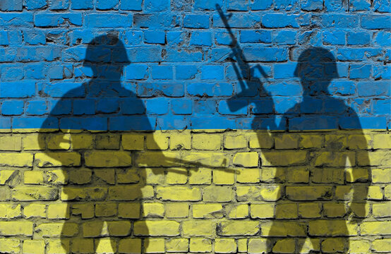 Schattenbilder von zwei Soldaten vor Ziegelwand mit Ukrainefahne
