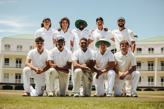 Team of cricket players posing on the field in white uniforms