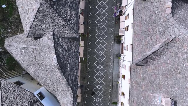Top Down View of Gjirokast&euml;r&rsquo;s Cobblestone Street.  A vertical aerial view capturing the patterned cobblestone street of Gjirokast&euml;r framed by traditional stone rooftops. The geometric design and hist