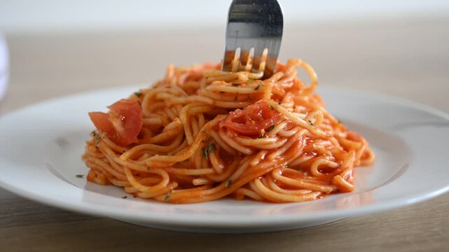 Twisting spaghetti with fork over plate. Close up