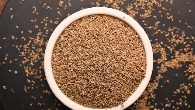 Top View of Carom Seeds (Ajwain) in White Bowl on Black Background &ndash; Rotating Footage