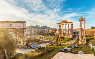 Panoramic view of Roman Forum with Arch of Septimius Severus and columns of Temple of Saturn at sunrise in Rome city, Italy. Ancient temple ruins, historic churches and archaeological remains