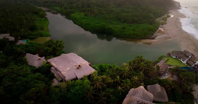 Resort on Piedras river mouth entering ocean at Los Naranjos beach, aerial