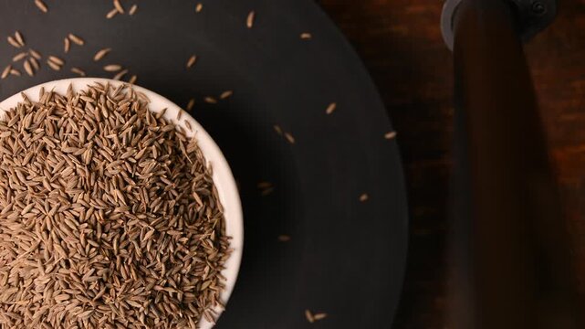 Top View of Cumin Seeds (Jeera) in White Bowl on Black Background &ndash; Rotating Footage