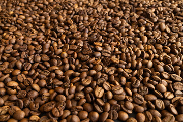 Fototapeta premium Close-up macro shot of roasted coffee beans filling the entire frame with rich brown tones