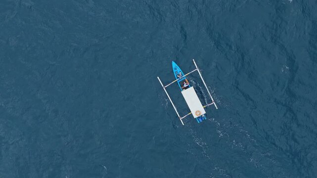 Traditional balinese jukung fishing boat navigating open blue sea
