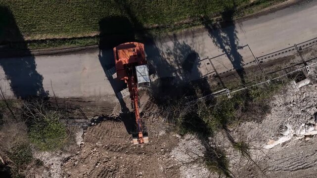Excavator operating on a construction site, moving earth and debris with its hydraulic arm and bucket, representing large scale development and demolition work
