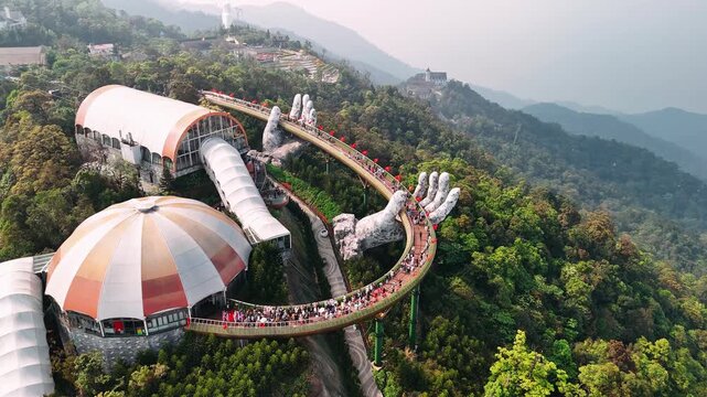 Aerial view of the golden bridge in ba na hills, vietnam. Tourists walking on the iconic pedestrian bridge supported by giant stone hands