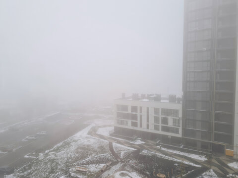 Tall residential building and low-rise apartment block in dense fog in winter Lviv, Ukraine