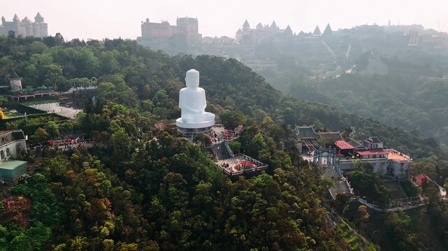 Aerial view of the buddha statue at ba na hills in da nang, vietnam with the french village in the background