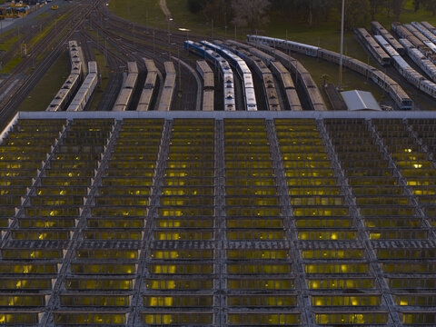 Aerial view of the train depot with its geometric roof reflecting the fading light, revealing rows of parked trains ready for their next journey, Roma, Lazio, Italy.