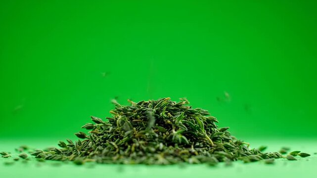 Close-up of dried thyme leaves gently falling onto a mound of fresh, aromatic herb. Perfect for culinary, cooking, and seasoning projects.