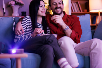 Obraz premium Couple having fun watching TV at home at night