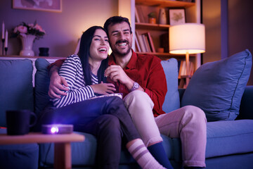 Couple having fun watching TV at home at night