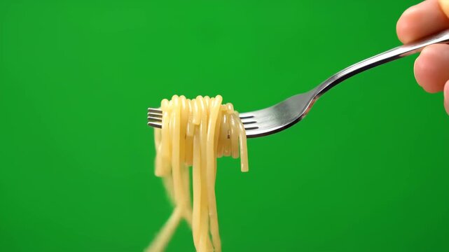 Close-up shot of freshly cooked spaghetti twirling on a fork, isolated on a bright green screen.