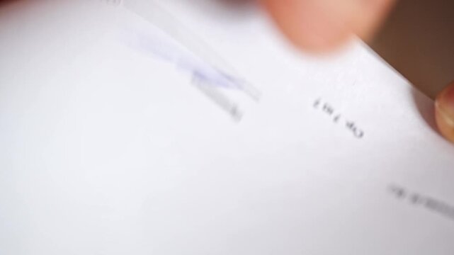 Person signs contract on paper with red pen in clear view