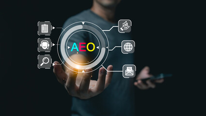 Businessman holding virtual AEO or Answer Engine Optimization digital hologram with marketing and technology icons on dark background