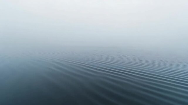 Showing open water forming gentle parallel ripples after light breeze at sea, fog obscuring horizon