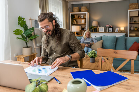 Freelance AI expert working at desk on laptop and reports while businesswoman uses digital tablet, remote collaboration, innovation consulting and multitasking work session