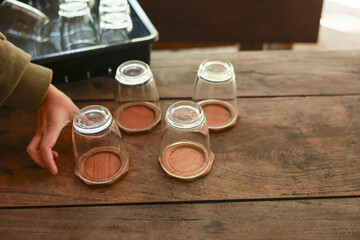 Child hand arranging simple empty glass on wood coaster. calm, quiet moment at home showing detail...
