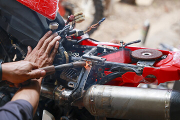 Mechanic concentrated hands welding motorcycle frame. Close up on repair work as skilled worker...