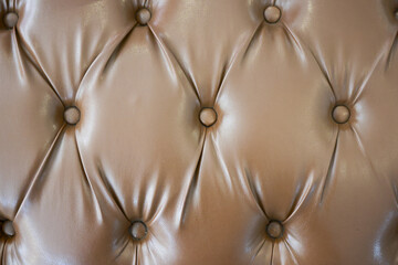 Fototapeta premium Luxurious gold leather tufted upholstery background showing classic pattern. rich texture and elegant buttons create comfortable and opulent feeling