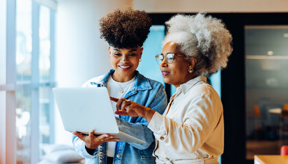 Older and younger women collaborate on tablet in office