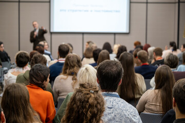 Obraz premium Business conference presentation with audience focused on speaker and projected slides, collaborative learning atmosphere, professional networking and knowledge sharing.