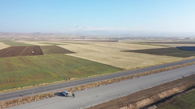 Agricultural farmland fields forming patchwork patterns across flat plain, drone moves forward crops, textures, rural landscape, distant mountains.