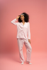 Fototapeta premium Stylish young woman posing confidently in comfortable loungewear on a soft pink background