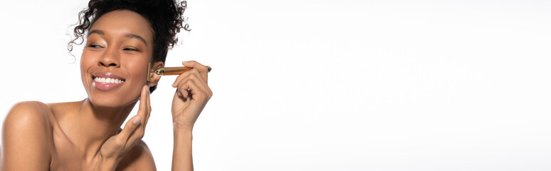 Obraz premium Young stylish woman enjoying a beauty routine with a facial roller in a bright setting