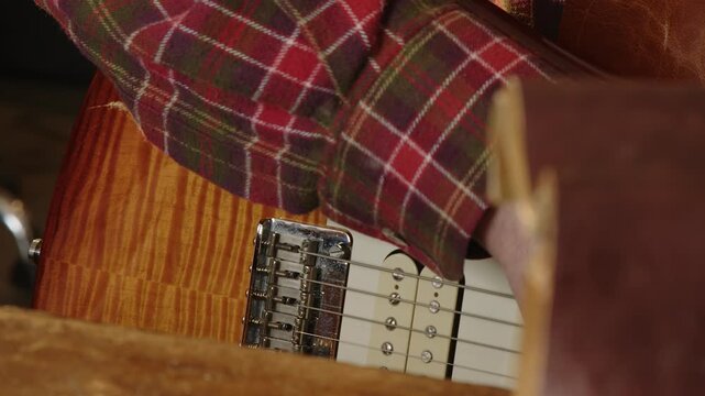 Guitar tech adjusts bridge intonation with screwdriver, closeup strings