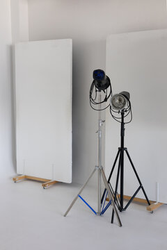 Equipment in a photo studio. Lighting stands with lamps on a white cyclorama background.