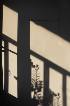 slanting rays of sunlight on a wall in a room, play of light and shadow, vertical image