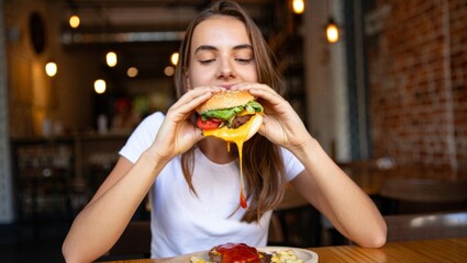 Happy Young Woman Enjoying a Cheeseburger in a Cozy Caf&eacute;