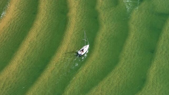bateau &agrave; voile se frayant un chemin au dessus de bancs de sable &agrave; mar&eacute;e basse sur le Bassin d'Arcachon, Gironde, France, Nouvelle-Aquitaine