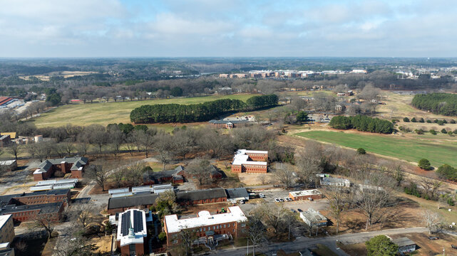 Dorothea Dix Park in Raleigh with open green fields, trees, historic buildings, and surrounding urban landscape.