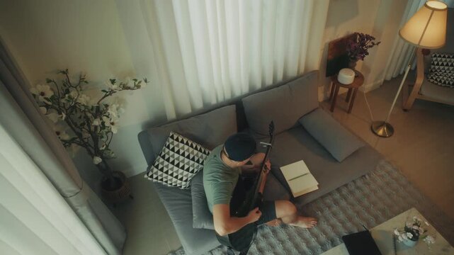 Man Creating Music. Person Sitting Barefoot Crafting Tunes With Acoustic Guitar And Notebook