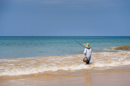 Fischer mit Angelrute an asiatischem Strand
