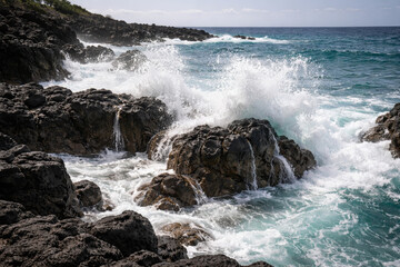 Obraz premium Waves crashing against rocky coastline with turquoise water