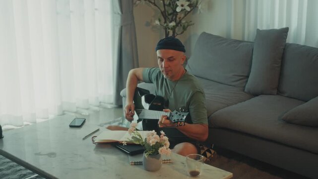 Man Adjusting Guitar Comfortably Indoors. Casual Musician Finetuning Strings In Relaxed Environment