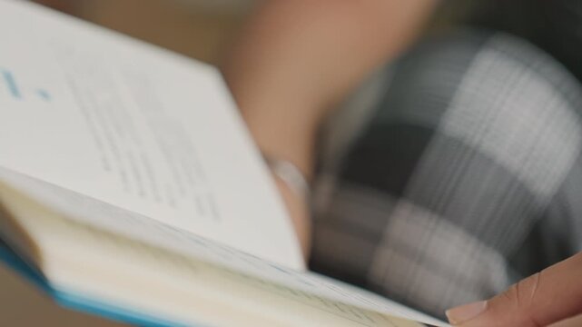 Hands flipping pages. Fingers turning pages with gentle rhythm. Closeup of hands flipping through textured paper pages. Intimate shot of fingers and ring during slow page turning in hotel setting