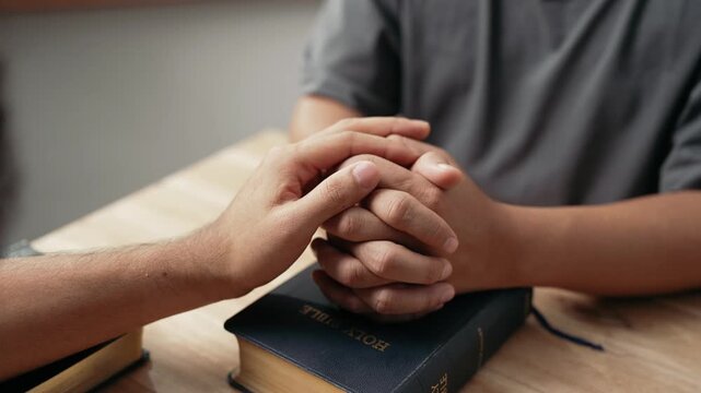 Christian worship and pray. Christian group of people holding hands praying worships together to believe and Bible on wooden table for devotional for prayer meeting concept.