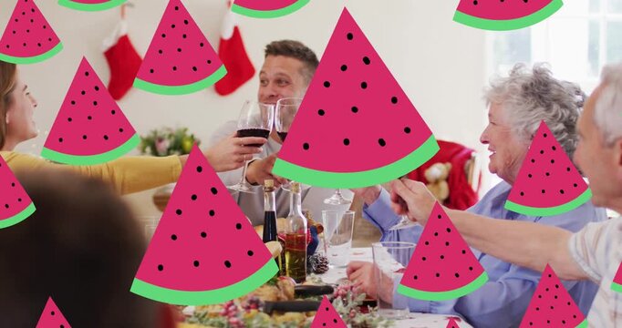 Animation of watermelon icons over caucasian family having christmas dinner