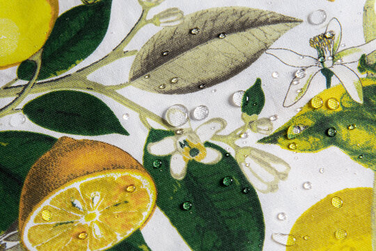 A beautiful and bright square tablecloth featuring a vibrant Mediterranean print of yellow lemons, green leaves, white blossoms, birds, and butterflies. 