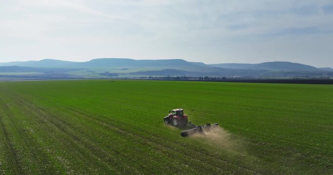 Tractor with a roller tillage on agricultural field at spring, aerial view. Soil rolling supports germination and is the basis for good harvesting