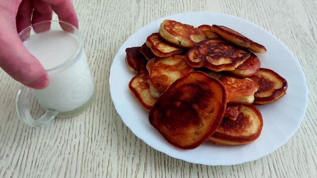 Freshly made golden pancakes stacked on a wooden table, served with a glass of milk. A cozy breakfast scene with warm tones, soft light, and delicious homemade comfort food vibes