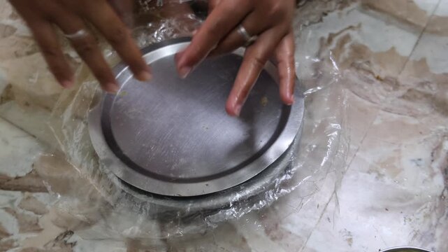 Close-up of hands flattening dough on a rolling board to make traditional Indian papad