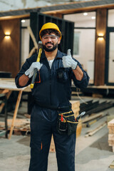 Everything is fine, showing thumb up. Portrait of a male carpenter posing in a woodworking workshop