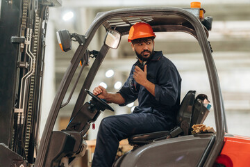 Naklejka premium Ready to load. Warehouse worker operating a forklift while handling wooden materials